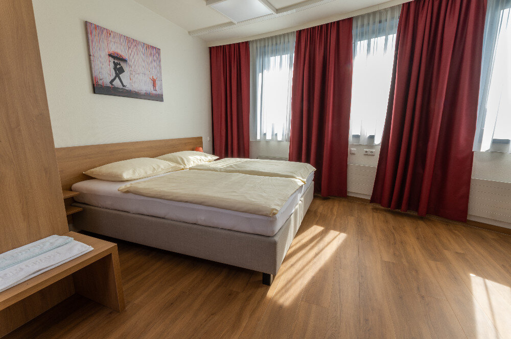 Twin room with red curtains and parquet floor